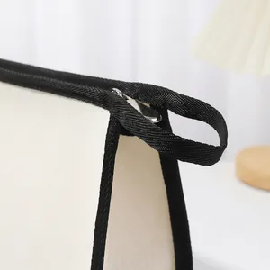 Détail en gros plan de la fermeture éclair et de la poignée en sangle noire du sac en toile