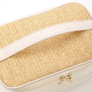 Detailed close-up of straw woven texture and heart zipper pulls on toiletry bag