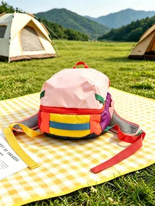 Multicolor patchwork nylon backpack on a yellow picnic mat in a scenic outdoor camping field
