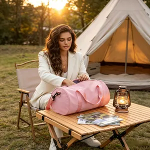 Woman sitting at a camping table organizing a pink waterproof cylindrical sport duffel bag