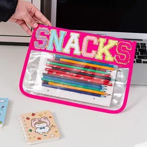 Close-up of a pink PVC storage bag with 'SNACKS' glitter embroidery holding color pencils.