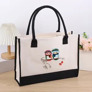 Detailed view of a spacious canvas tote bag with a cute cartoon owl print and black trim