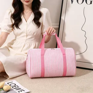 Detailed view of the pink and white striped seersucker travel bag held by a model