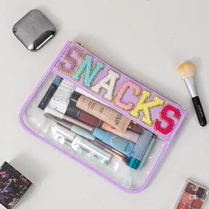 Detail of purple PVC makeup bag with SNACKS chenille patches and visible cosmetics