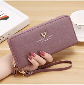 Close-up of women's mauve clutch wallet featuring lychee texture and gold stag decor