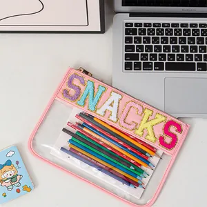 Close-up of pink clear PVC pouch featuring colorful glittery embroidered SNACKS text