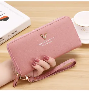 Detail view of pink long leather zipper wallet with gold deer emblem and wrist strap