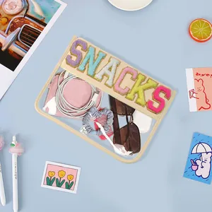 Transparent PVC pouch with 'SNACKS' embroidery, showcasing storage capacity and design.