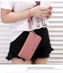 Detail view of a pink litchi pattern long zipper wallet clutch with wrist strap