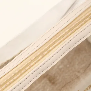 Primer plano del detalle de la cremallera crema y la textura tejida en el bolso.