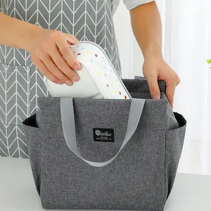 Close-up of putting a lunch box into a gray insulated bento bag with handle