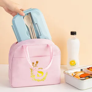 Detail of pink insulated lunch bag with letter S, showing bento box being tucked inside.