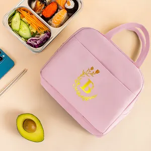 Pink insulated lunch bag with golden initial B floral print in a food scene setup