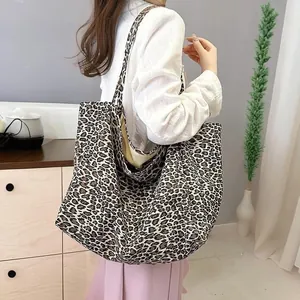 Detail view of a large leopard print canvas tote bag on a model's shoulder.