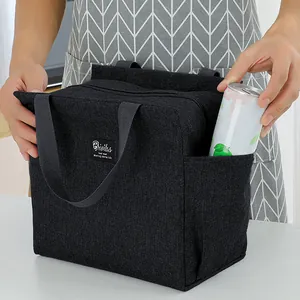 Detail of hand putting a can into the side pocket of a black insulated lunch bag.