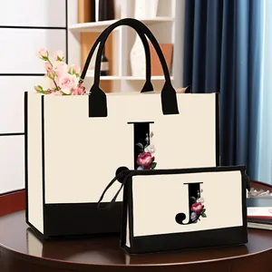 Vue détaillée de l'ensemble sac fourre-tout et trousse de toilette en toile avec lettre 'J'