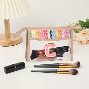 Close-up of clear PVC makeup bag with rainbow woven trim and pink letter C embroidery