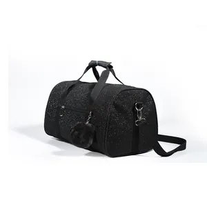Close-up view of a black glitter sports duffel bag featuring a soft pom-pom charm accessory