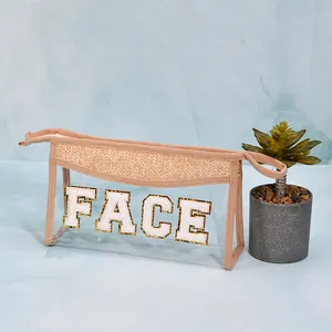 Detail of straw-trimmed PVC makeup bag featuring a 'FACE' chenille patch embroidery.