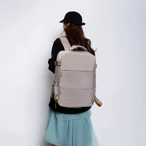 Detailed view of a large khaki travel backpack worn by a model in a minimal setting.
