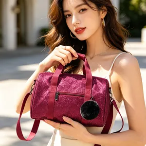 Detailed view of a glittering burgundy gym bag with a stylish black fur pom-pom charm