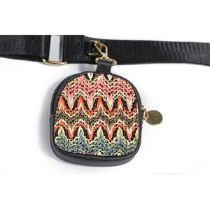 Close-up of a bohemian woven accessory pouch featuring a colorful zigzag pattern and metal clip