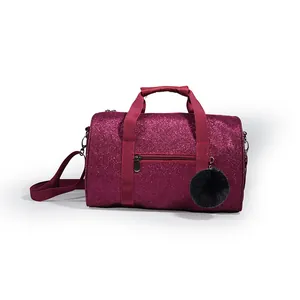 Detailed close-up of a sparkling magenta glitter dance bag featuring a fuzzy black pompom