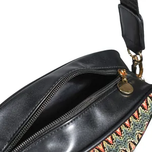 Detailed view of women's woven crossbody bag showing top zipper and ethnic pattern
