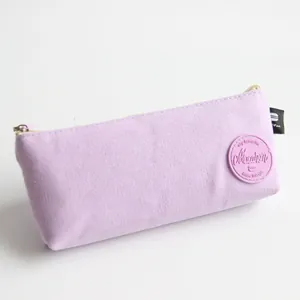 Detail view of a Morandi purple canvas pencil case with a round Macaron patch logo.