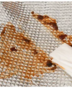 Macro view of waterproof aluminum foil insulation bag lining being wiped clean with tissue