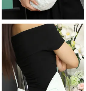 Vue détaillée d'un sac dumpling blanc texturé porté par un mannequin en tenue noire.