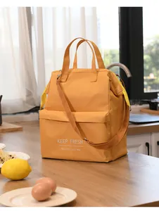 Yellow insulated lunch bag with 'KEEP FRESH' print, handles and shoulder strap in kitchen
