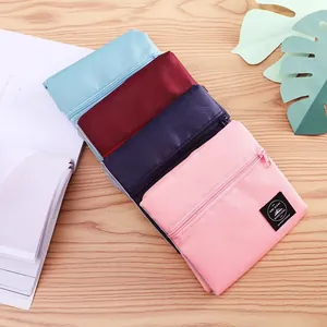 Set of four colorful foldable travel storage pouches with zipper closure on wooden surface.