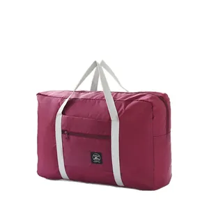 Large capacity burgundy foldable travel storage bag with white handles for luggage
