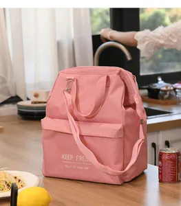 Macro view of pink insulated lunch bag with shoulder strap in a modern kitchen setting.