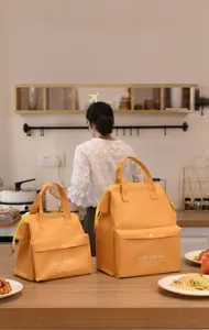 Two vibrant orange insulated lunch bags in large and small sizes on a kitchen counter.