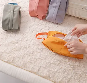 Demonstration of putting clothes into a portable orange waterproof travel storage bag