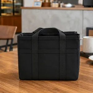 Vista detallada de una bolsa tote de lona negra con varias capas en una mesa de café