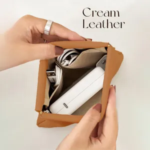 Detailed macro view of brown leather self-closing storage pouch for power bank and cables.