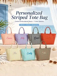 Seven colorful striped canvas tote bags with personalized embroidery on a beach