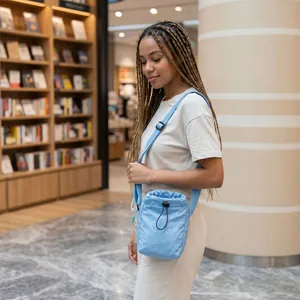 Lifestyle detail of a blue nylon drawstring bag worn by a model in a bookstore.