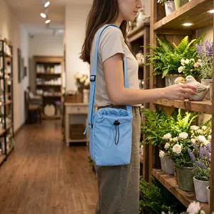 Light blue nylon drawstring crossbody bag shown in a casual lifestyle setting