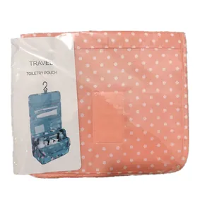 Detail view of a folded pink polka dot toiletry pouch with a product description card
