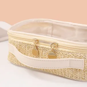 Detailed close-up of a straw woven travel cosmetic bag with golden zippers and transparent top