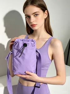 Model holding a lightweight purple nylon drawstring crossbody bag for sports and travel