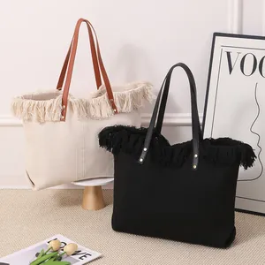 Detalle de dos grandes bolsos tote tejidos con flecos en beige y negro con asas de cuero.