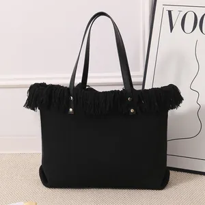 Detalle del bolso tote de lona negra con elegantes flecos y detalles de tachuelas