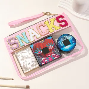 Detail view of pink transparent PVC pouch with vibrant SNACKS chenille embroidery