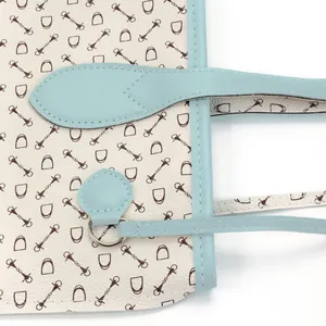 Close-up showing the horse bit pattern and light blue leather trim of a tote bag.