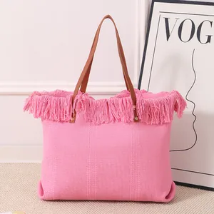 Detalle del bolso tote grande rosa tejido con flecos bohemios y asas de color marrón